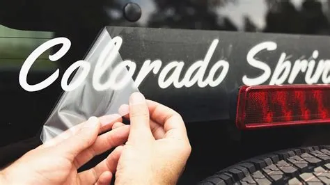 Installer applying a custom decal to a vehicle window, highlighting careful craftsmanship